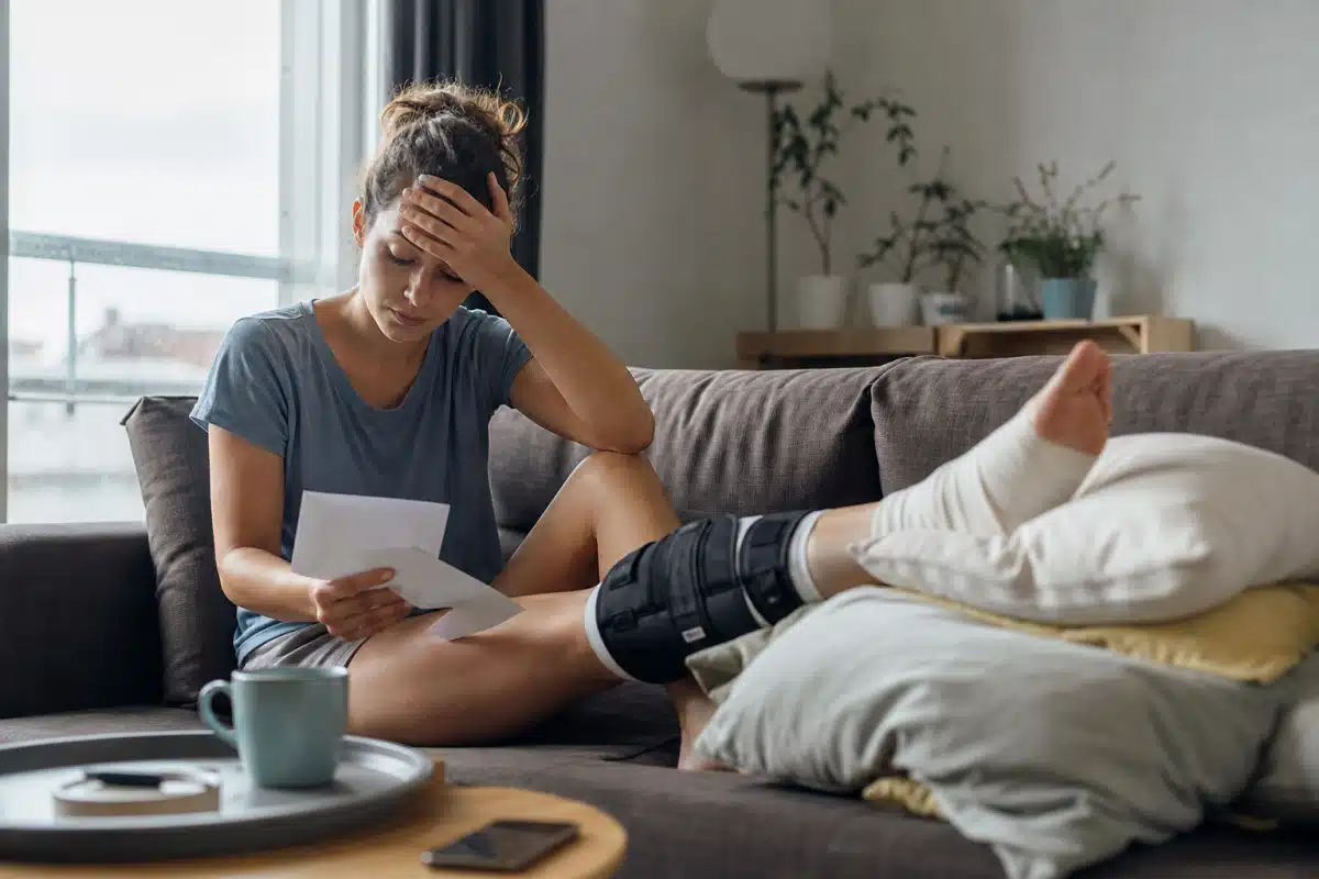 Personne assise sur canapé avec attelle lisant courrier